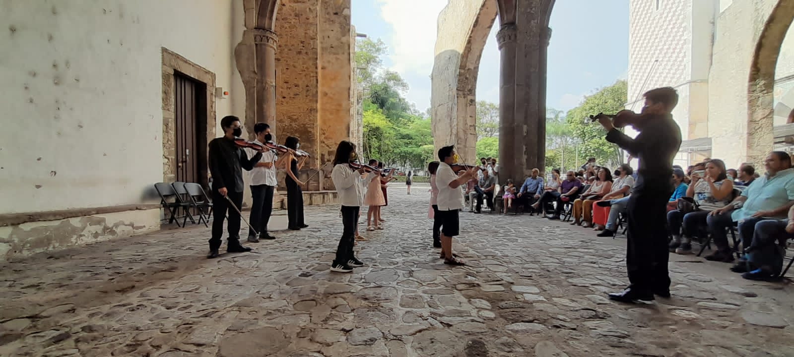Ensamble de violines dirigidos por un profesor